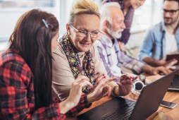 Young volunteers help senior people on the computer