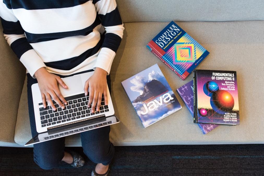 woman with laptop and coding textbooks