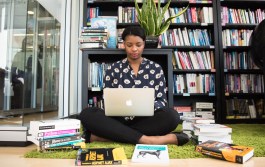 woman studying on laptop surrounded by programming books